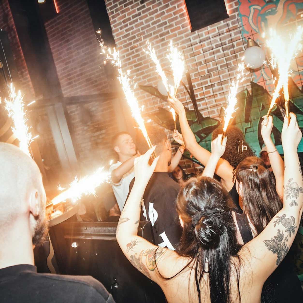 young people celebrating with light spark in a club